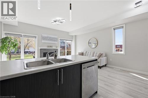 Kitchen island featuring a double basin stainless steel sink, dark wood-finish cabinetry, and a built-in stainless steel dishwasher - 37 Delena Avenue S, Hamilton, ON - Indoor Photo Showing Kitchen With Double Sink