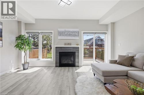 Spacious living area featuring light wood-finish flooring, a contemporary fireplace with dark tile surround, and a white mantel - 37 Delena Avenue S, Hamilton, ON - Indoor Photo Showing Living Room With Fireplace