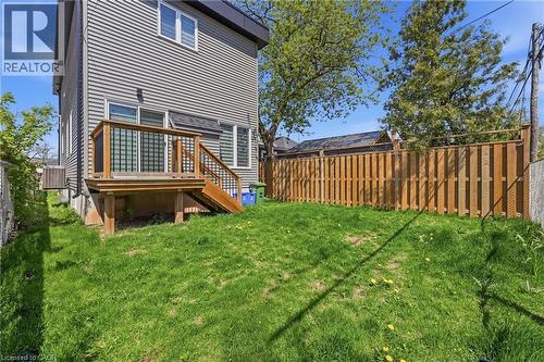 Spacious backyard featuring a wooden privacy fence, a raised wood deck with staircase access, and gray horizontal siding - 37 Delena Avenue S, Hamilton, ON - Outdoor
