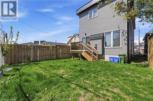 Expansive green space featuring a large lawn area, a wood deck with stairs, a sliding glass door entry, and horizontal siding - 37 Delena Avenue S, Hamilton, ON - Outdoor