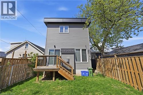 Rear exterior featuring gray horizontal siding, a flat roofline, and a raised wooden deck with stairs - 37 Delena Avenue S, Hamilton, ON - Outdoor