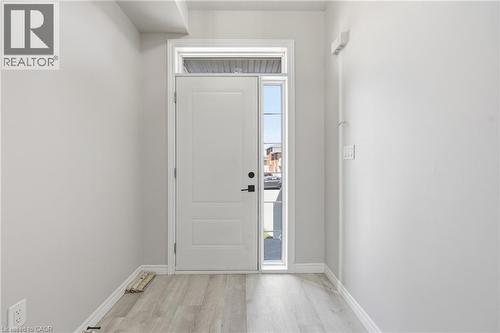 Entryway featuring a white paneled door with black hardware, a transom window, a side lite, light gray walls, and wood-finish flooring - 37 Delena Avenue S, Hamilton, ON - Indoor Photo Showing Other Room