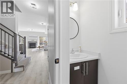 Powder room featuring a single vanity with a white countertop, under-mount sink, and a circular mirror - 37 Delena Avenue S, Hamilton, ON - Indoor Photo Showing Bathroom