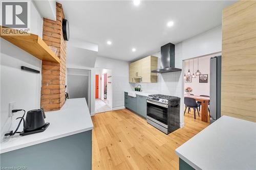 Kitchen featuring wood-finish flooring, white countertops, and a brick accent wall - 501 Ferguson Avenue N, Hamilton, ON - Indoor Photo Showing Kitchen