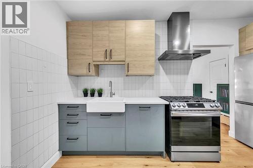Kitchen featuring wood-finish upper cabinetry, light blue lower cabinetry, white subway tile backsplash, white countertop, and a white farmhouse sink - 501 Ferguson Avenue N, Hamilton, ON - Indoor Photo Showing Kitchen With Upgraded Kitchen