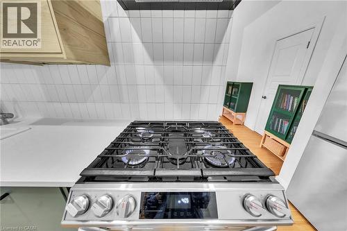 Stainless steel gas range with a visible flame, set against a white subway tile backsplash - 501 Ferguson Avenue N, Hamilton, ON - Indoor Photo Showing Kitchen