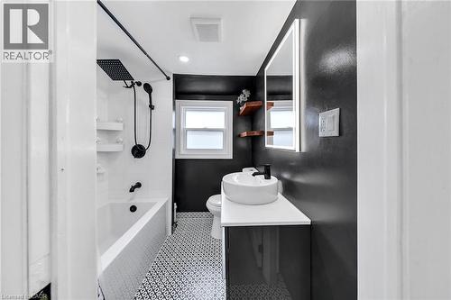 Bathroom featuring a shower-over-tub combination with black fixtures, white subway tile surround, patterned floor tiles, and a floating vanity with vessel sink - 501 Ferguson Avenue N, Hamilton, ON - Indoor Photo Showing Other Room