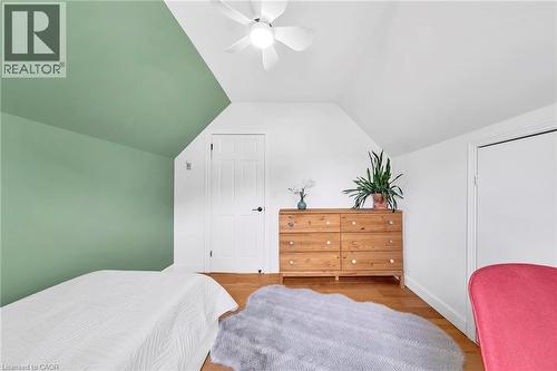 Attic room featuring a sloped ceiling, wood-finish flooring, a white ceiling fan, a white paneled door, and white baseboards - 501 Ferguson Avenue N, Hamilton, ON - Indoor Photo Showing Bedroom