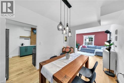 Open-concept dining area featuring wood-finish flooring, a linear pendant light fixture with clear glass shades, and a wood dining table - 501 Ferguson Avenue N, Hamilton, ON - Indoor