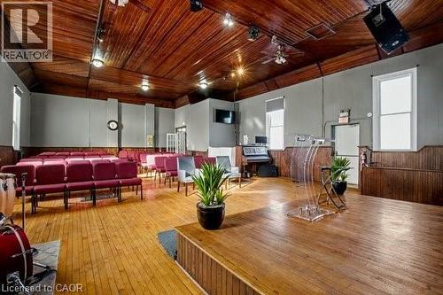 Spacious room featuring wood-finish flooring, a raised stage, and exposed wood ceiling panels - 37 Wellington Street, Cambridge, ON 
