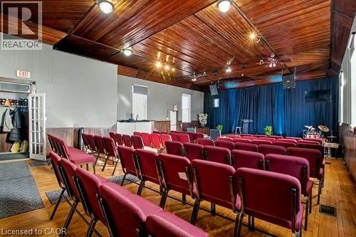 Spacious assembly room featuring a wood-panel ceiling, wood-finish flooring, recessed lighting, and white wainscoting - 37 Wellington Street, Cambridge, ON 