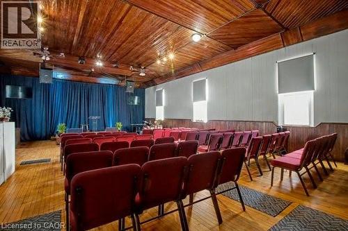 Large gathering space featuring wood-finish flooring, a wood-paneled ceiling, and a stage area with blue drapery - 37 Wellington Street, Cambridge, ON 