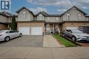 Townhome exterior featuring brick and siding facade, two white garage doors, a concrete walkway, and a covered porch with white railings - 53 Prosperity Drive, Kitchener, ON  - Outdoor With Facade 