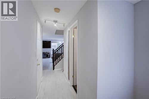 Hallway featuring light wood-finish flooring, white walls, white doors with brass-finish hardware, and track lighting - 53 Prosperity Drive, Kitchener, ON - Indoor Photo Showing Other Room