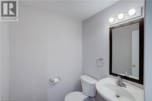 Powder room featuring a wall-mounted sink with chrome faucet, a dark-framed mirror, and a three-light vanity fixture - 53 Prosperity Drive, Kitchener, ON - Indoor Photo Showing Bathroom