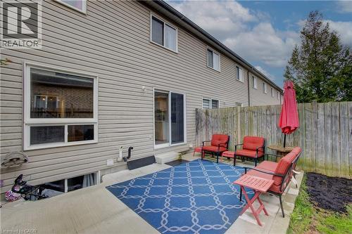 Rear concrete patio featuring a sliding glass door entry, a large window, and light-toned horizontal siding - 53 Prosperity Drive, Kitchener, ON - Outdoor With Exterior
