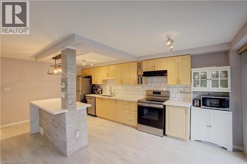 Kitchen featuring light wood cabinetry, stainless steel appliances, white subway tile backsplash, and light wood-finish flooring - 53 Prosperity Drive, Kitchener, ON - Indoor Photo Showing Kitchen