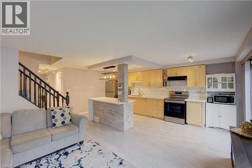Open-concept living space featuring wood-finish flooring, a kitchen with light wood cabinetry, white subway tile backsplash, and stainless steel appliances - 53 Prosperity Drive, Kitchener, ON - Indoor Photo Showing Other Room
