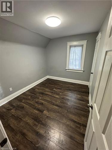 Room featuring wood-finish flooring, light grey painted walls, white baseboards, and a white ceiling with a flush-mount light fixture - 61 Waterloo Drive, Kitchener, ON - Indoor Photo Showing Other Room
