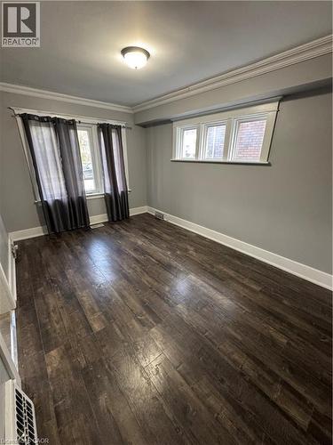 Spacious room featuring rich wood-finish flooring, crisp white baseboards, and elegant crown molding - 61 Waterloo Drive, Kitchener, ON - Indoor Photo Showing Other Room