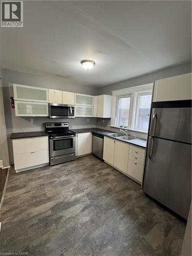 Kitchen featuring white cabinetry, dark countertops, stainless steel appliances, and wood-finish flooring - 61 Waterloo Drive, Kitchener, ON - Indoor Photo Showing Kitchen With Double Sink