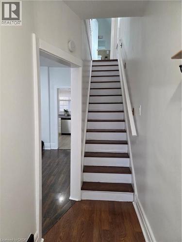 Staircase with dark wood-finish treads and white risers, complemented by a white handrail - 125 Cavell Avenue, Hamilton, ON - Indoor Photo Showing Other Room