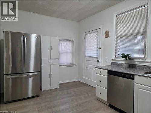 Kitchen featuring stainless steel appliances, wood-finish flooring, white cabinetry, and abundant natural light from multiple windows - 125 Cavell Avenue, Hamilton, ON - Indoor Photo Showing Kitchen