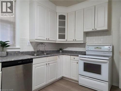Kitchen featuring white shaker-style cabinetry, a stainless steel dishwasher, an electric range, and a subway tile backsplash - 125 Cavell Avenue, Hamilton, ON - Indoor Photo Showing Kitchen With Double Sink