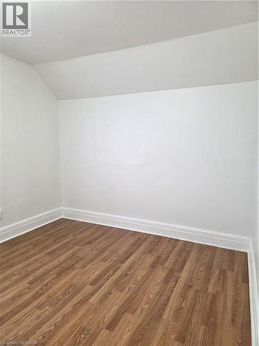 Room featuring wood-finish flooring, white walls, white baseboards, and a sloped ceiling - 125 Cavell Avenue, Hamilton, ON - Indoor Photo Showing Other Room
