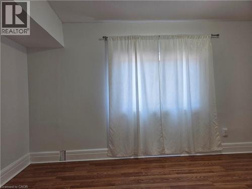 Window with sheer white curtains, wood-finish flooring, white baseboards, and neutral wall paint - 125 Cavell Avenue, Hamilton, ON - Indoor Photo Showing Other Room