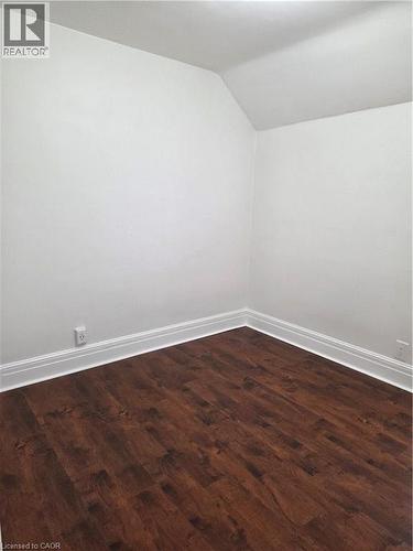 Interior room featuring wood-finish flooring, white baseboards, and a white wall finish with a sloped ceiling detail - 125 Cavell Avenue, Hamilton, ON - Indoor Photo Showing Other Room