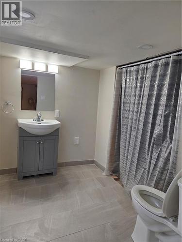 Bathroom featuring a gray vanity with an integrated sink, a rectangular wall-mounted mirror, and a three-light fixture above - 125 Cavell Avenue, Hamilton, ON - Indoor Photo Showing Bathroom