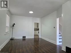 Spacious room featuring wood-finish flooring, white baseboards, and a window with blinds - 