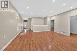 Spacious open-concept interior featuring wood-finish flooring, recessed lighting, and neutral wall tones - 