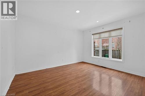 Room featuring wood-finish flooring, white baseboards, recessed lighting, and a large window with a roller shade - 704 Stone Church Road E, Hamilton, ON - Indoor Photo Showing Other Room
