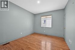 Kitchstone-finish countertops, stainless steel refrigerator, white electric range, and wood-finish flooring - 