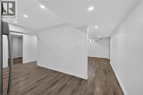 Room featuring wood-finish flooring, light grey walls, white trim, and a white paneled door - 704 Stone Church Road E, Hamilton, ON - Indoor Photo Showing Other Room