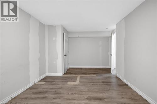 Room featuring wood-finish flooring, light gray wall paint, and a double-door closet with paneling - 704 Stone Church Road E, Hamilton, ON - Indoor Photo Showing Other Room