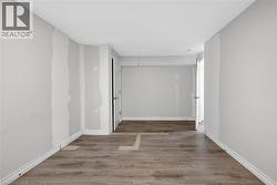 Room featuring wood-finish flooring, light gray wall paint, and a double-door closet with paneling - 