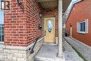 Front entrance featuring a yellow door with oval glass insert, brick facade, stone base, and exterior wall lantern - 704 Stone Church Road E, Hamilton, ON  - Outdoor 