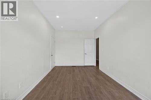 Spacious interior room featuring wood-finish flooring, recessed lighting, neutral wall tones, white trim, and a paneled door - 704 Stone Church Road E, Hamilton, ON - Indoor Photo Showing Other Room