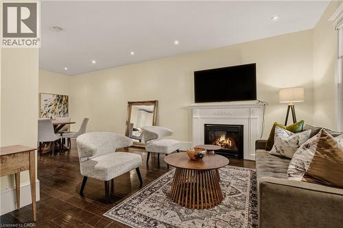Living area with a white mantel fireplace, dark wood-finish flooring, recessed lighting, and light-colored walls - 104 Barnesdale Avenue N, Hamilton, ON - Indoor Photo Showing Living Room With Fireplace