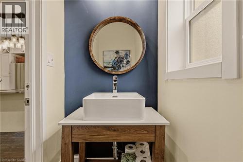Vessel sink with a chrome faucet, set on a wood-finish vanity with a light-colored countertop - 104 Barnesdale Avenue N, Hamilton, ON - Indoor Photo Showing Bathroom