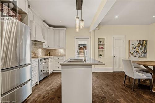 Modern kitchen featuring white cabinetry, stainless steel appliances, a center island with sink, wood-finish flooring, and recessed lighting - 104 Barnesdale Avenue N, Hamilton, ON - Indoor Photo Showing Kitchen With Stainless Steel Kitchen With Double Sink