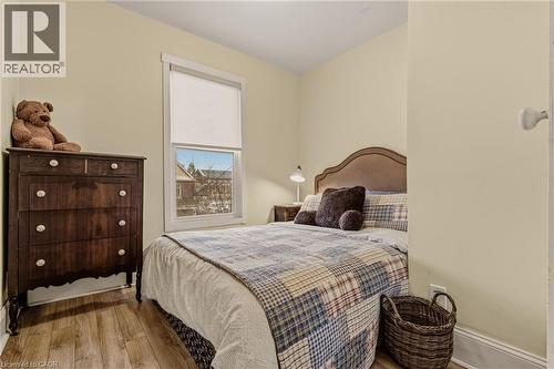 Bedroom featuring wood-finish flooring, a window with roller shade, and light-toned walls - 104 Barnesdale Avenue N, Hamilton, ON - Indoor Photo Showing Bedroom