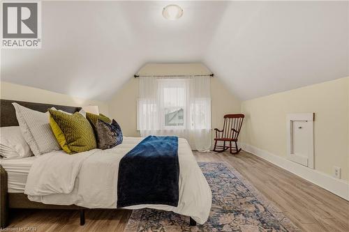 Room featuring sloped ceilings, a single window with sheer curtains, wood-finish flooring, and a built-in access panel - 104 Barnesdale Avenue N, Hamilton, ON - Indoor Photo Showing Bedroom