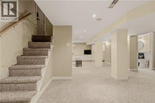 Carpeted staircase with wooden handrail leading to a finished lower level - 104 Barnesdale Avenue N, Hamilton, ON - Indoor Photo Showing Other Room