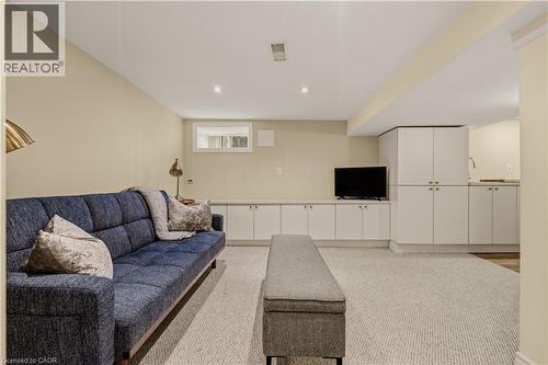 Recessed lighting illuminates this space featuring a built-in media console, extensive white cabinetry, a compact window, and light-toned carpeting - 104 Barnesdale Avenue N, Hamilton, ON - Indoor