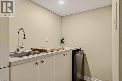 Wet bar featuring a stainless steel sink with a gooseneck faucet, light-toned cabinetry with dark hardware, a light-toned countertop, and an integrated stainless steel appliance - 104 Barnesdale Avenue N, Hamilton, ON - Indoor
