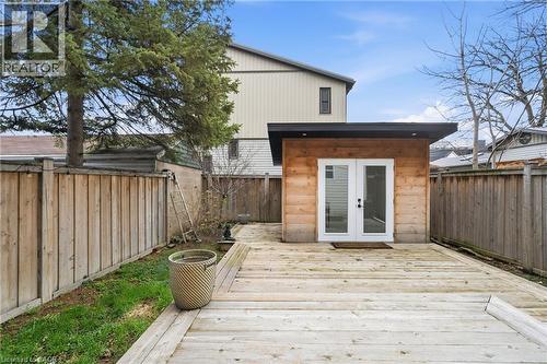 Private backyard featuring a detached structure with wood paneling and double glass doors, surrounded by a wood fence - 104 Barnesdale Avenue N, Hamilton, ON - Outdoor With Exterior